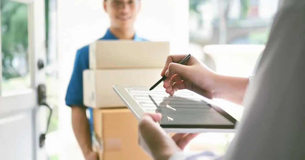 ¨Photo of a person receiving a delivery of packages and signing a form